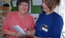 Two health admin staff looking at a paper and smiling
