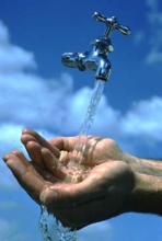 hands under a water tap against a blue sky