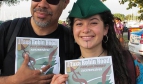 A couple  holding Robin Hood Tax posters and wearing Robin Hood caps